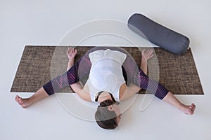 Female yoga instructor doing Tortoise Pose or Kurmasana asana exercise.
