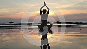 Female in yoga meditation pose at amazing sunset on the sea.