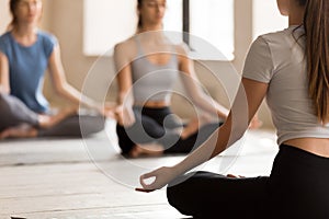 Female yoga teacher meditate with students in lotus position