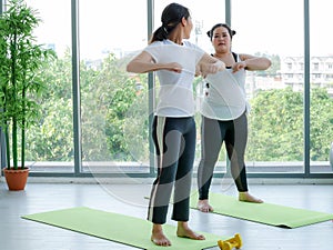 Female yoga trainner teaching fat overweight woman to proactice on the mat