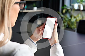 Female young businesswomans hands holding cell phone with empty blank screen.