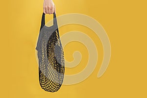 Female young hand holds empty black vintage reusable eco-friendly string bag. The concept of recycling, environmental care,