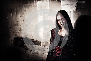 Female zombie corpse standing in front of grunge wall in abandoned house. Horror and Ghost concept. Halloween day festival and