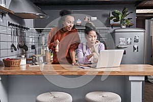 Females discussing recipes while preparing dinner at kitchen