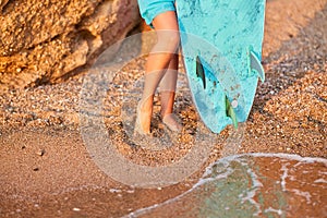Females feet on wet sand near ocean with board for surf. Beach time and summer time idea. Adventure and surfing concept