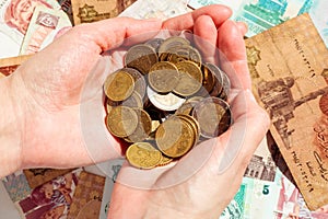 Females hands with Euro coins above the colorful banknotes background