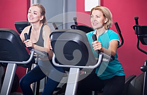 Females riding stationary bicycles in gym