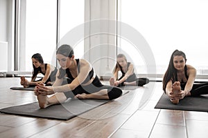 Females taking up Head to Knees Pose on mats indoors