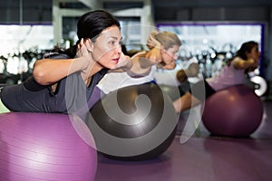 Females working out with aerobic ball in modern gym