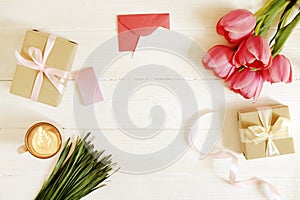 Femenine composition of woman`s workspace w/ blank greeting card, envolope & presents for mother`s day. Coffee cup with latte ar