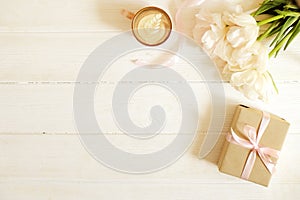 Femenine composition of woman`s workspace w/ blank greeting card, envolope & presents for mother`s day. Coffee cup with latte ar