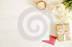 Femenine composition of woman`s workspace w/ blank greeting card, envolope & presents for mother`s day. Coffee cup with latte ar