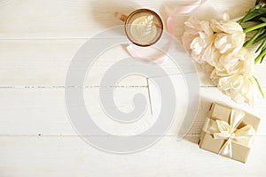 Femenine composition of woman`s workspace w/ blank greeting card, envolope & presents for mother`s day. Coffee cup with latte ar