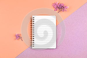 Femenine workspace concept with blank white notebook, mockup with colorful dried flowers on a desktop, top view and flat