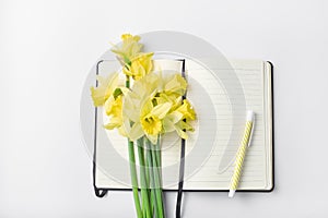 femine workspace. white work desk with notepad, pen and bouquet spring flower. photo