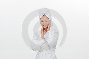 feminine adult older woman wearing bathrobe and towel over her head smiling isolated over white background