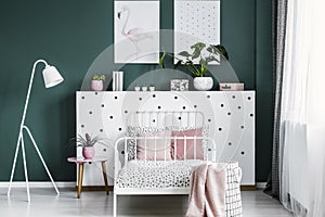 Feminine bedroom interior with a bed, bedside table, lamp, plant