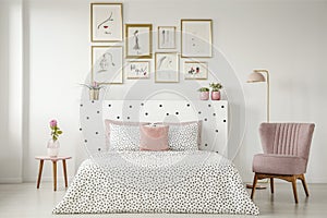 Feminine bedroom interior with a double bed with dotted sheets,