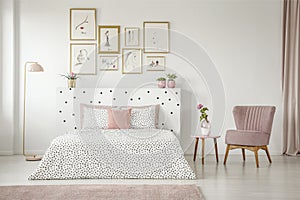 Feminine bedroom interior with white walls, polka dot bedding, p