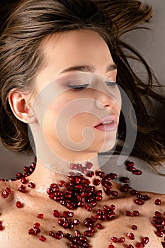 Feminine brunette girl with beautiful makeup and pomegranate seeds