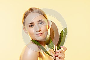 Feminine. Close up of beautiful female face with green leaves over white background. Cosmetics and makeup, natural and