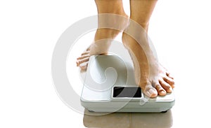 Feminine feet about to stand on a weighing scale.