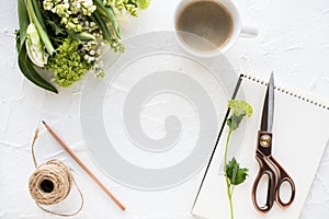 Feminine flatlay with flowers and ccoffee on white tabletop