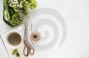 Feminine flatlay with flowers and ccoffee on white tabletop