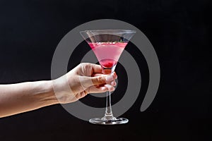 Feminine hand holding elegant glass with cranberry alcoholic cocktail