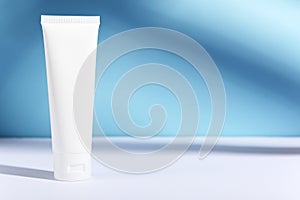 Feminine hygienic product tube on sunny blue background with shadow. Shampoo, hand cream, toothpaste white package side view.