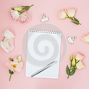 Feminine office workspace. Notebook copyspace. Flat lay, social media, top view. Pink flowers and tea on pastel pink background.