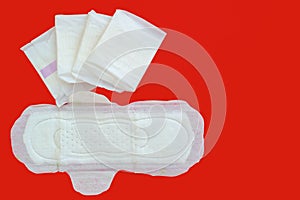 Feminine sanitary napkin, an absorbent item worn by a woman while menstruating, on red background