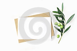 Feminine stationery, desktop mock-up scene. Blank horizontal greeting card and craft envelope with olive branch.White