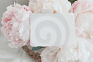 Feminine wedding, birthday mockup scene. Closeup of blank cotton paper card, invitation on pink floral petals. Peony