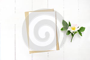 Feminine wedding stationery, floral desktop mock-up scene. Blank greeting card, craft envelope and blooming wild rose