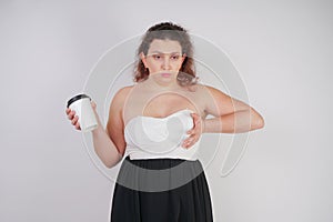 Feminine woman with plus size body in a fashionable dress holding a paper Cup of coffee and posing on a white background in the St