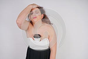 Feminine woman with plus size body in a fashionable dress holding a paper Cup of coffee and posing on a white background in the St