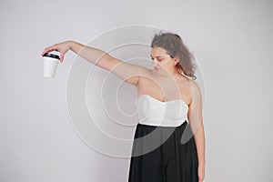 Feminine woman with plus size body in a fashionable dress holding a paper Cup of coffee and posing on a white background in the St