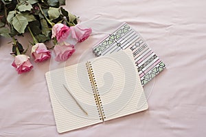 Feminine workplace concept. Freelance fashion comfortable femininity workspace in flat lay style with open notebook, pink rose flo