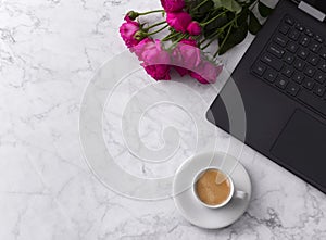 Feminine workspace with laptop computer, bouquet of roses and coffee on a marble table.