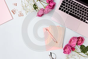 Feminine workspace with laptop, rose flowers and office supply