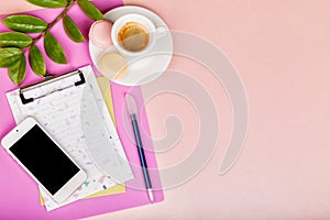 Feminine workspace with paper blank, pen, green branch, smartphone, cup of coffee. Flat lay, top view