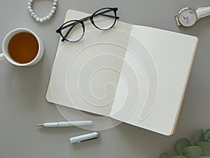 Feminine workspace top view mockup. Glasses over an opened notebook with copy space and eucalyptus
