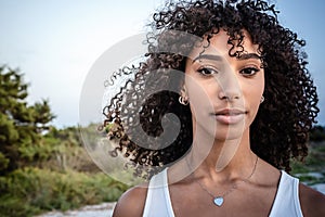 Femininity and beauty in nature: close up portrait of beautiful black Hispanic young woman with curly dark long hair looking