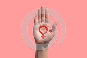 Feminism icon in hand on pink background, power of women background concept