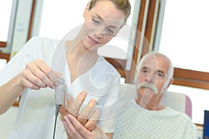 Femle nurse fitting oxymeter to senior patient at hospital