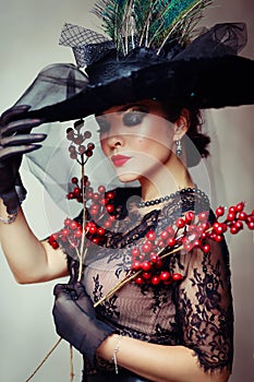 Femme fatale woman in black hat with feathers red lips