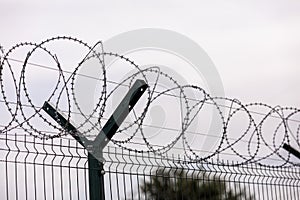 Fence of barbed metal wire against the background of clouds, the concept of freedom, unfreedom, close up