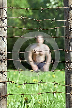 Fence with barbed wire on the foreground and a man on the background