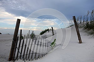 Fence buried in sand dunes and pretty skies